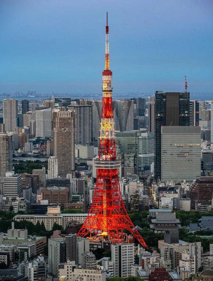 Before: Tokyo Tower at night, with the lights of the tower stretched downward into vertical ribbons of colour.